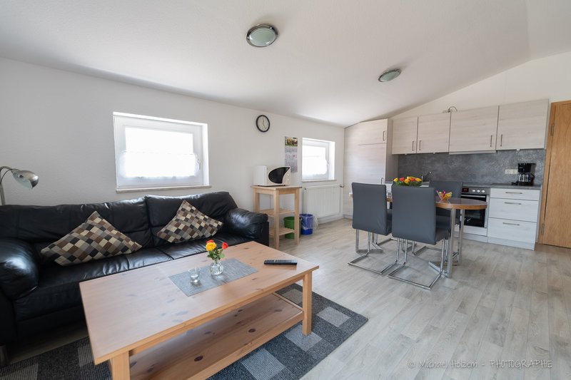 Wohnzimmer mit Couch und Küchenzeile – Ferienwohnung Ferienhof Wick